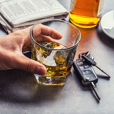 Glass of whiskey with car keys nearby, representing impaired driving risks