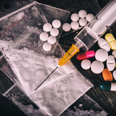 Syringe with pills and powder-filled bags, emphasizing the risks of drug misuse