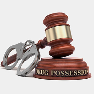 Gavel resting on a sound block engraved with 'DRUG POSSESSION' next to a pair of handcuffs, illustrating how to Contest Drug Possession Charges in Florida.